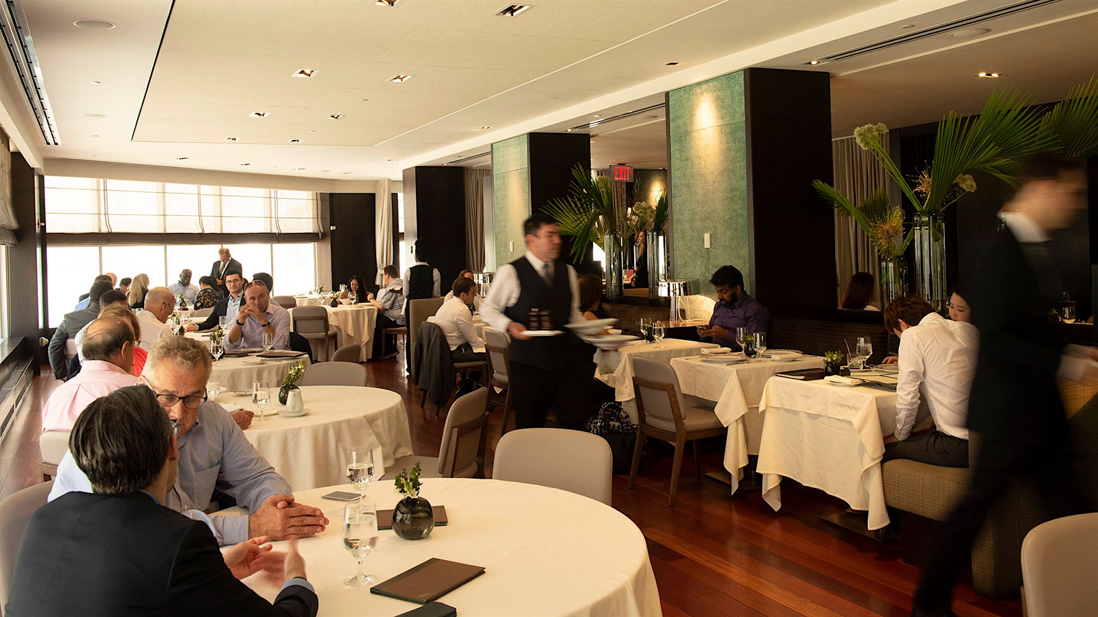 People in the modern-design dining room of Ai Fiori, with a member of the restaurant’s staff carrying plates through